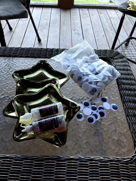 Craft supplies laid out — googly eyes, glitter glue, and a star-shaped dish