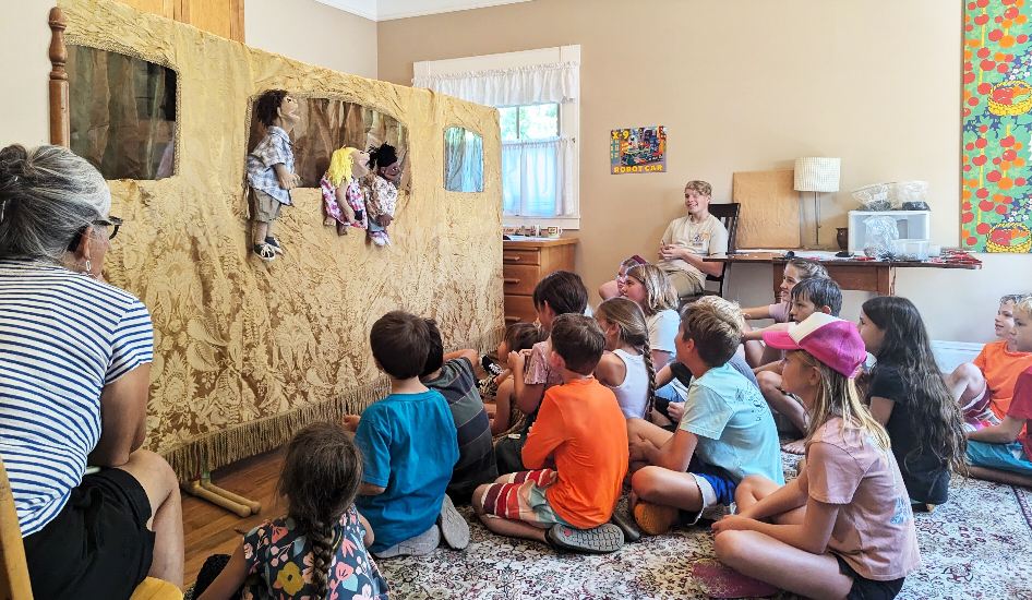 Children watching a puppet show with an engaged audience