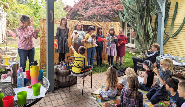 Children performing a puppet show under a garden pergola
