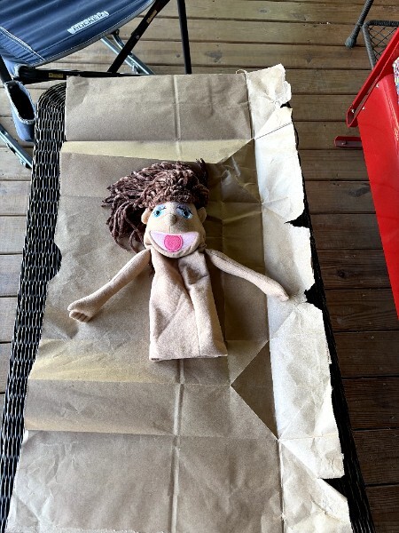 A puppet laid on a paper bag pattern to trace the outline