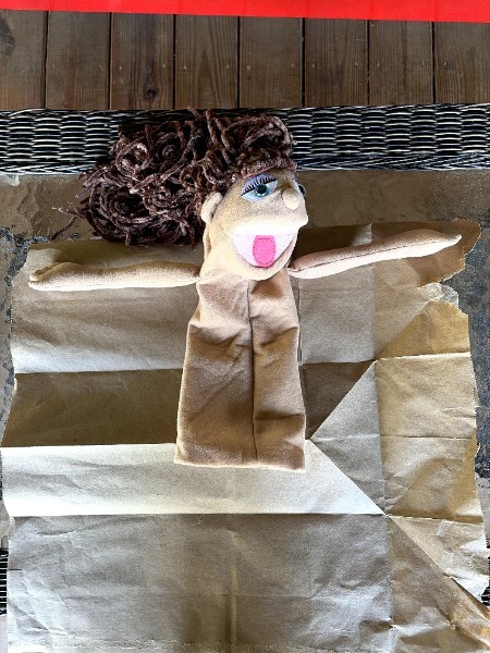 Puppet wearing a paper bag costume pattern during fitting