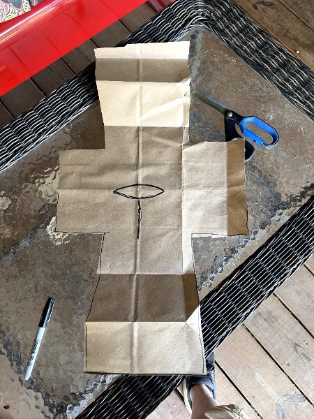 Cut paper bag pattern laid flat with the keyhole neck opening visible and scissors nearby